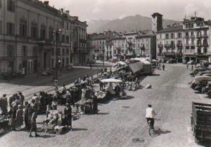 Piazza Grande a Locarno in una cartolina d'epoca, con le bancarelle del mercato e un ciclista
