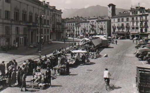 Piazza Grande a Locarno in una cartolina d'epoca, con le bancarelle del mercato e un ciclista
