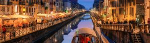 Il Naviglio Grande di Milano di sera, con un battello sul canale e i locali illuminati