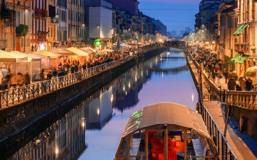 Il Naviglio Grande di Milano di sera, con un battello sul canale e i locali illuminati